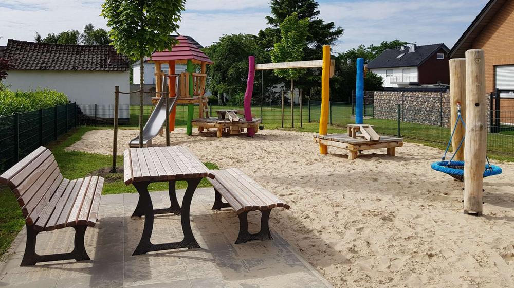 Blick auf den Spielplatz Lupinenweg mit Bänken und verschiedenen Spielgeräten