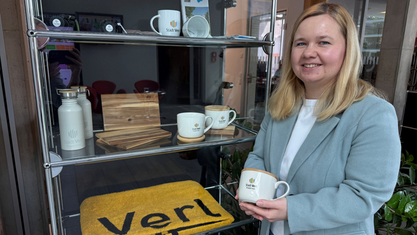 Jessica Dobinsky steht neber der Vitrine mit den Werbeartikeln.