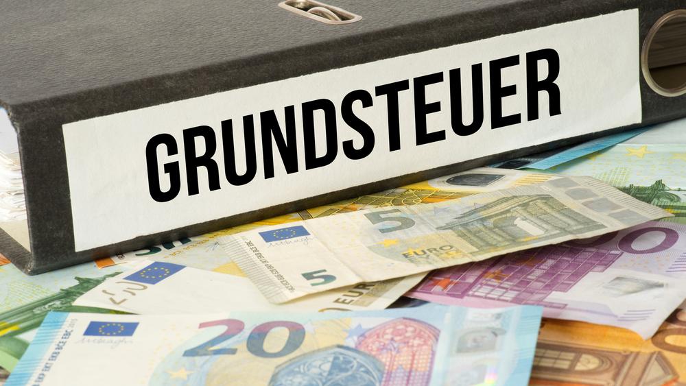 Aktenordner "Grundsteuer" und Geldscheine
