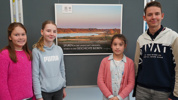 Amelie, Anna Lena, Emma und Jan Hendrik (v. l.) aus der UNESCO-Projektgruppe vor einem der Bilder aus der Ausstellung. 